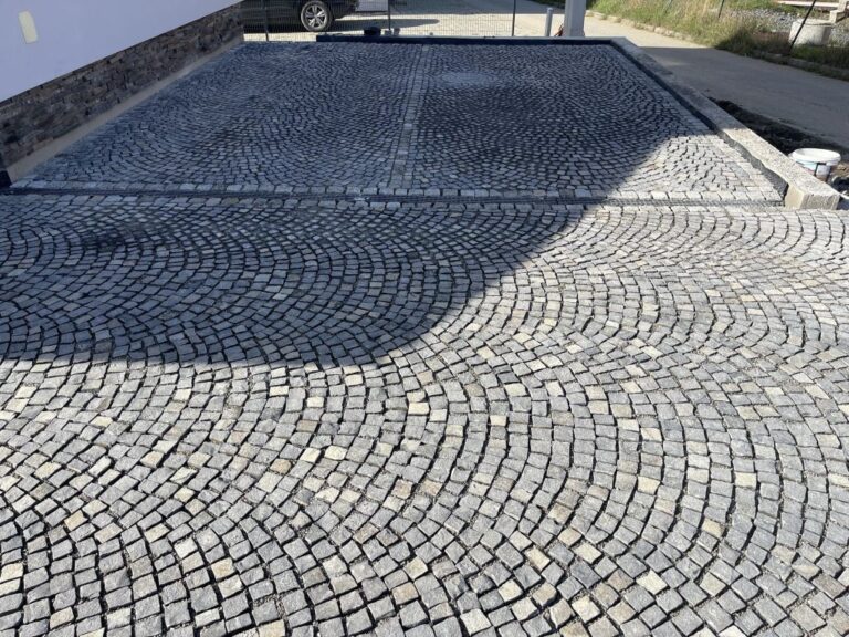 Közelről fotózott 4/6 cm-es kézi hasítású bazalt kockakő burkolat, átlapolt íves mintában, változatos szürke tónusokkal és precíz, hagyományos lerakással.