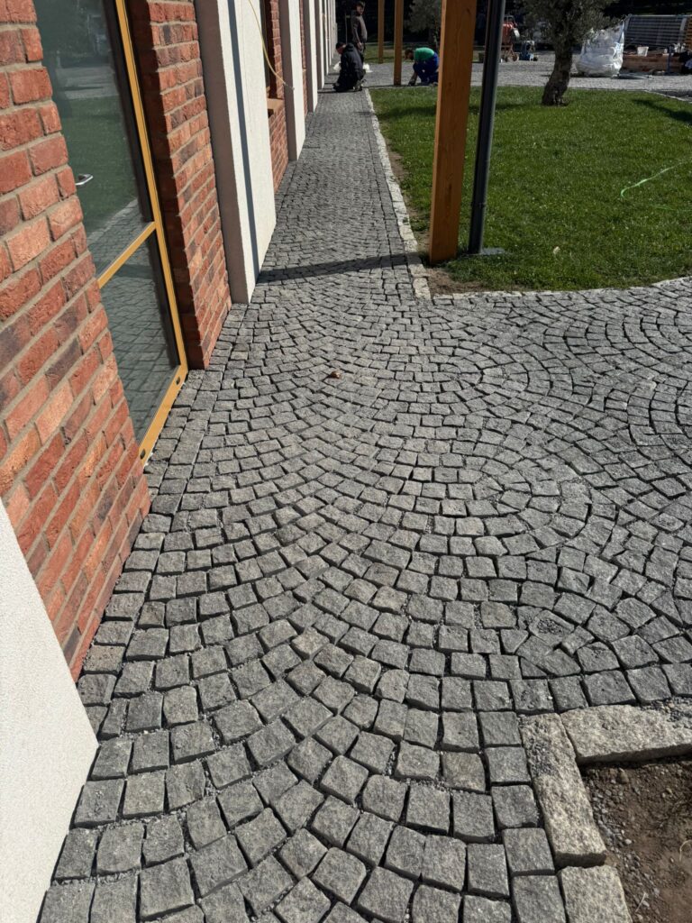 10×10×10 cm gabbró kockakő burkolat hasított felülettel, íves rakási mintával épület mellett