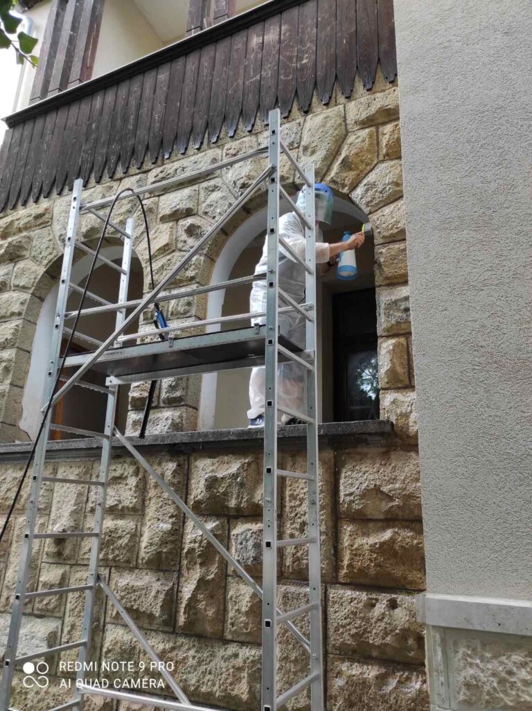 Kőfelület vegyszeres és kefés tisztítása állványról, a keleti homlokzaton