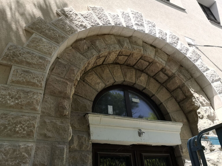 Kőburkolat elhelyezése hőszigetelt homlokzaton a boltív új és megmaradó kőelemeinek találkozásánál