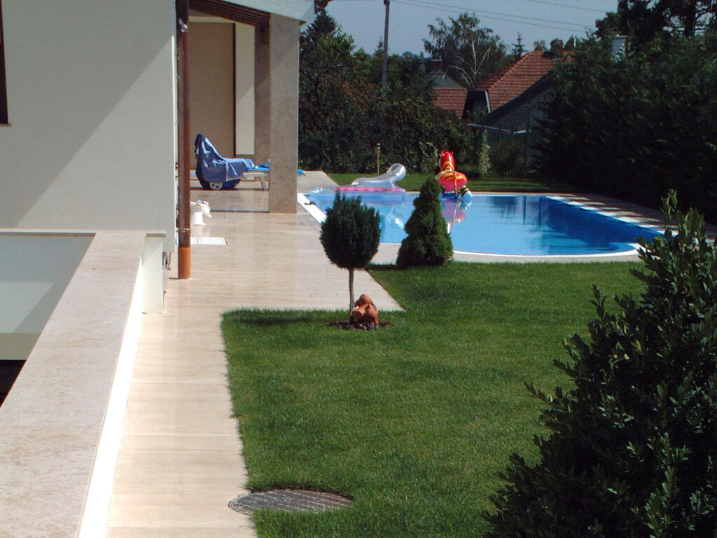 Természetes kő kültéri burkolat medence és kerti járda mellett, tartós kivitelezéssel